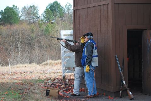1979 Ford F-150 - Men practice shooting at a clay pigeon range, with shotguns and a wooden building visible.