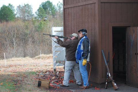 1979 Ford F-150 - Men practice clay shooting at an outdoor range with a wooden structure nearby.