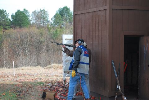 1979 Ford F-150 - Two individuals participate in a shotgun shooting event at an outdoor range, with a wooden structure in the background.