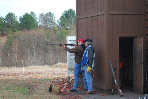 1979 Ford F-150 - Two men practice shooting at an outdoor clay pigeon range, with one man aiming a shotgun and the other observing.
