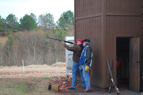 1979 Ford F-150 - Men practice shooting at a clay pigeon range with a wooden shelter and trees in the background.