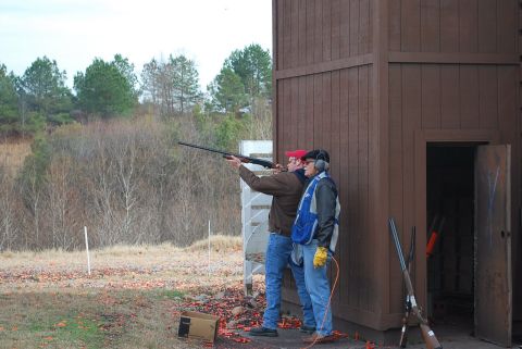 1979 Ford F-150 - Men practice shooting at a clay pigeon range with a wooden structure in the background.