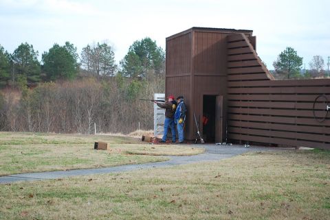 1979 Ford F-150 - Two men practice shooting at a clay pigeon range, with a wooden structure and fence in the background.