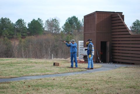 1979 Ford F-150 - Men practice trap shooting at an outdoor range with a wooden shelter and trees.