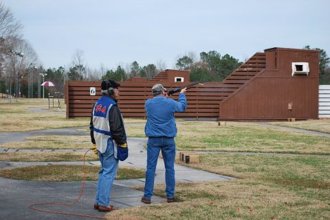 1979 Ford F-150 - Men practice trap shooting at an outdoor range with wooden structures and grassy areas.