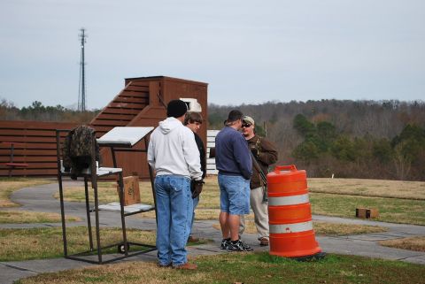 1979 Ford F-150 - Several people gather at an outdoor shooting range, with a cell tower visible in the distance.