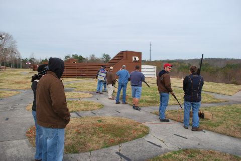 1979 Ford F-150 - A group of people are gathered at a clay shooting range, holding shotguns and preparing for their turn.