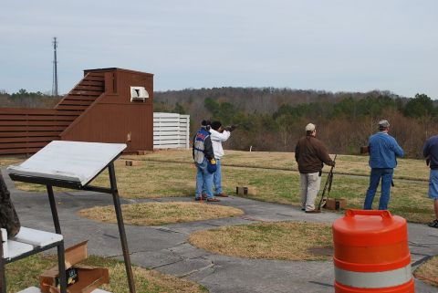 1979 Ford F-150 - People practice shooting at an outdoor range with a wooded area in the background.