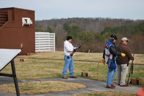 1979 Ford F-150 - Three men are at a shooting range, two of them holding shotguns, with a brown structure in the background.
