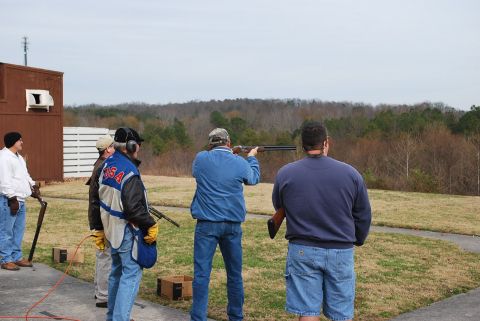 1979 Ford F-150 - People are gathered at an outdoor shooting range, with one person actively engaged in shooting a shotgun.