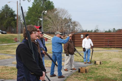 1979 Ford F-150 - A group of men are at a shooting range, with one man aiming his shotgun at a clay pigeon.