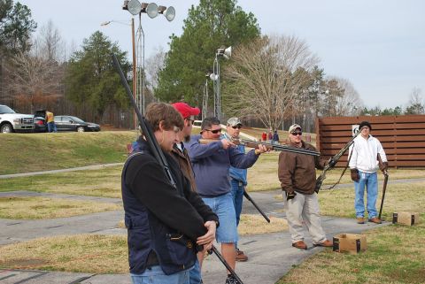 1979 Ford F-150 - Several men are gathered at an outdoor shooting range, some holding shotguns.