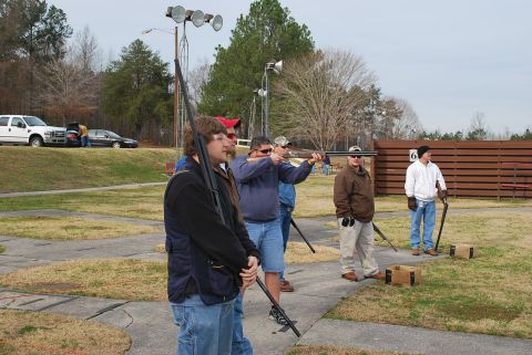 1979 Ford F-150 - Several individuals practice shooting at a clay pigeon range, with vehicles visible in the distance.