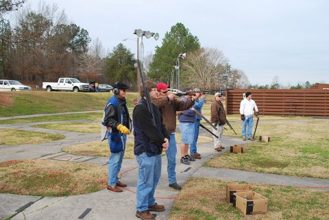 1979 Ford F-150 - A group of people practice shooting at a clay pigeon range on a cloudy day, with several vehicles parked nearby.