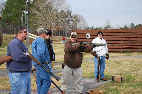 1979 Ford F-150 - Men participate in a shooting event at an outdoor range, with wooden barriers and trees in the background.