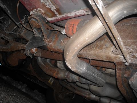 1995 Ford Bronco - The undercarriage of a vehicle displays significant rust on the exhaust system and suspension components.