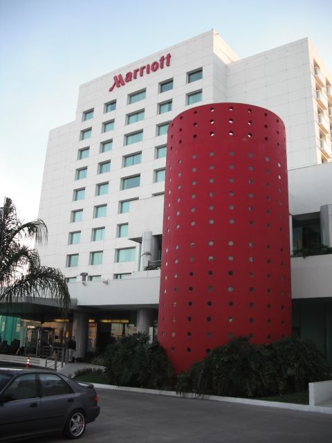 1991 Ford Bronco - Marriott hotel exterior a distinctive red cylindrical architectural element and a parked car.