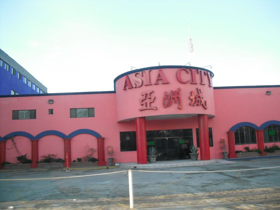 Building with "ASIA CITY" sign in red letters. Chinese characters below. Pink facade with blue arched windows