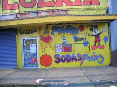1991 Ford Bronco - A brightly painted storefront displays cartoon characters and advertisements for piñatas, balloons, and cold sodas.