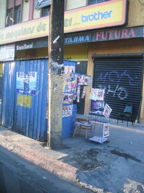 1991 Ford Bronco - A street scene shows a kiosk displaying magazines and a storefront with a black roll-up door covered in graffiti.