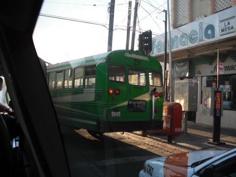 1991 Ford Bronco - A green and white bus is seen from the interior of another vehicle on a sunny day.