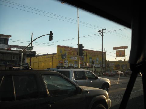 1991 Ford Bronco - View from a vehicle looking towards a street scene with several cars and a large yellow building displaying various advertisements.
