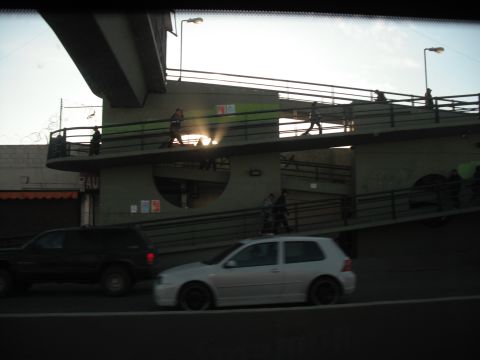 1991 Ford Bronco - Two vehicles pass by an elevated pedestrian walkway under a bright sky.