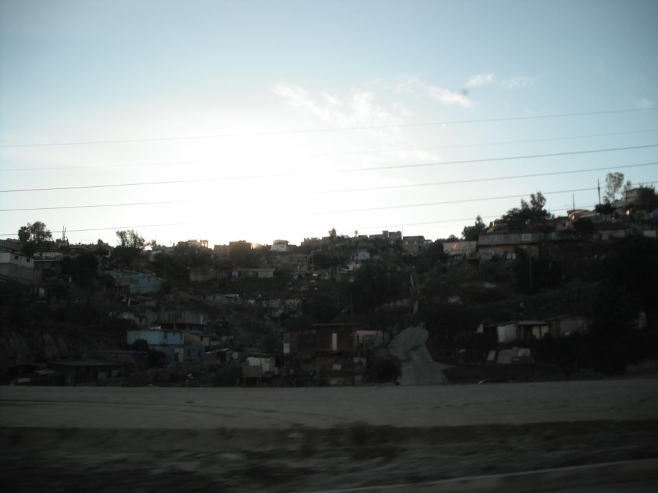 Hillside community with houses and power lines under a bright sky