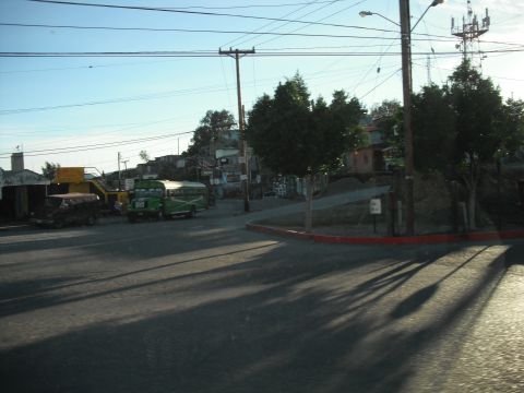 1991 Ford Bronco - A street scene with a green bus and a dark SUV under a clear sky.