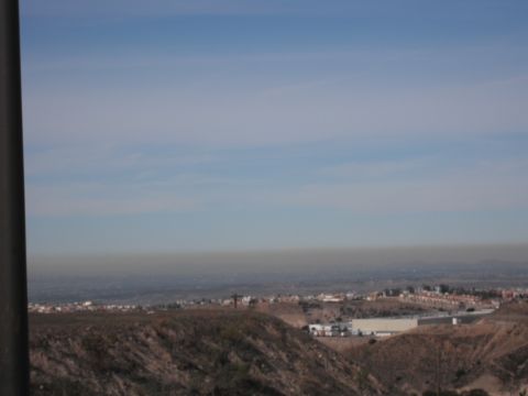 1991 Ford Bronco - A wide view of a landscape rolling hills, scattered buildings, and a hazy sky, suggesting a distant urban or suburban area.