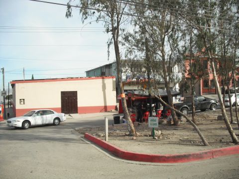 1991 Ford Bronco - A street scene with a white sedan and a black pickup truck near a food stand.