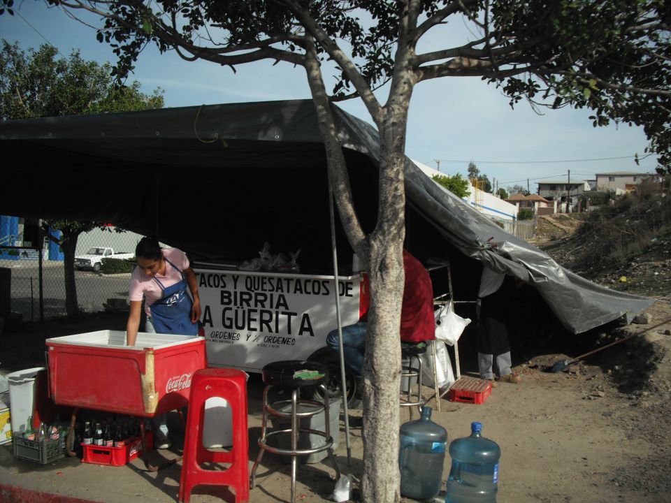 Taco stand with a black tarp, red cooler, and water jugs