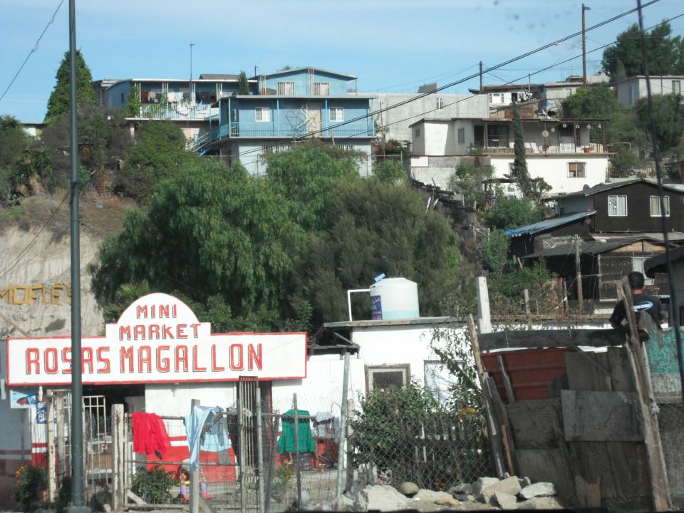 Mini Market Rosas Magallon sign with houses on a hillside behind it