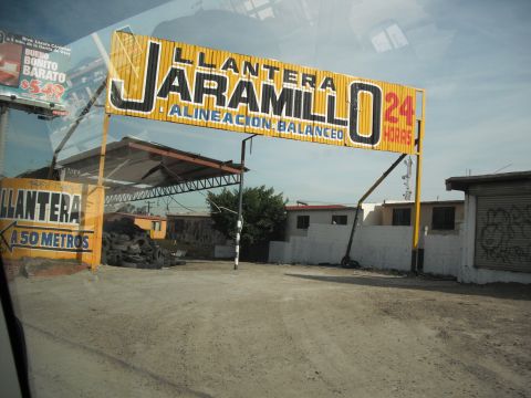 1991 Ford Bronco - A large yellow sign advertises Llanta Jaramillo, offering 24-hour tire services and alignment.