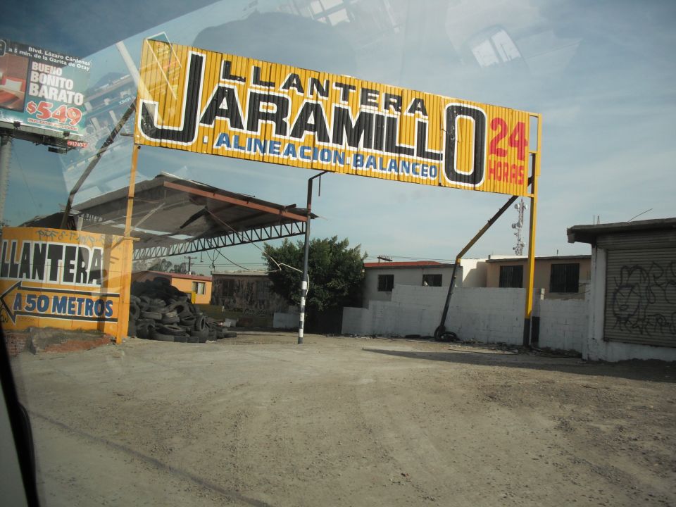 Yellow sign for Llanta Jaramillo 24 Horas with a pile of tires