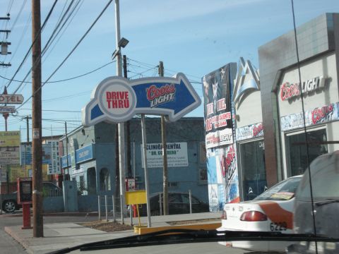 1991 Ford Bronco - A white car with an orange stripe and license plate 6229 is visible in the foreground, parked near a Coors Light drive-thru sign.