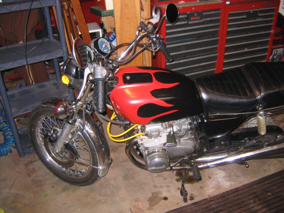 Motorcycle fuel tank with red and black flame decals, chrome fender, and dual gauges