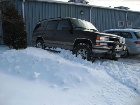 1998 Chevrolet Tahoe - This SUV is partially buried in a large snowbank, with its tires struggling for traction.
