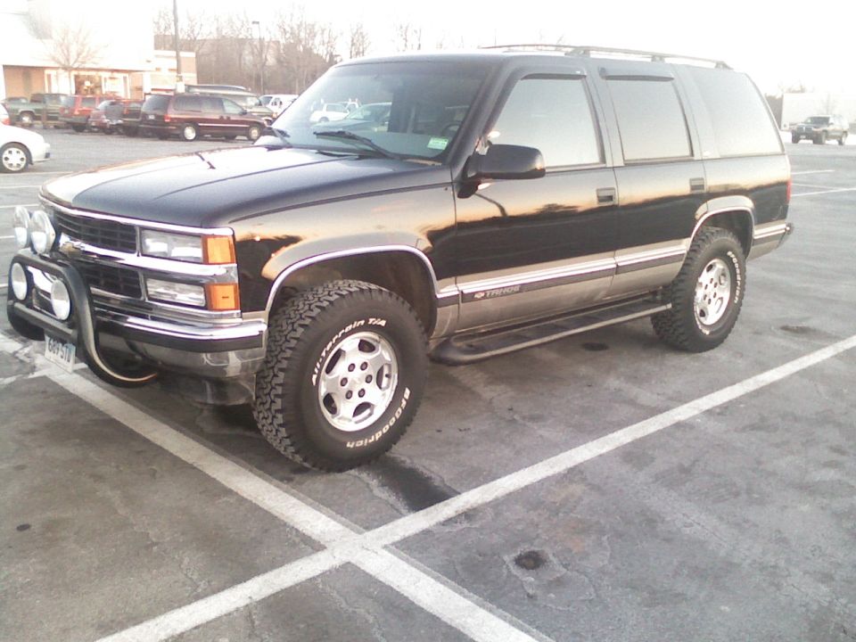 Black 1998 Chevrolet Tahoe SUV with chrome bull bar and fog lights, parked in a lot