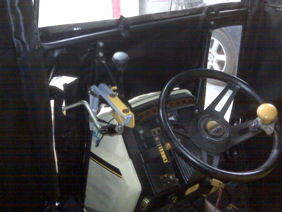 Garden tractor controls and steering wheel with spinner knob inside a black soft cab enclosure