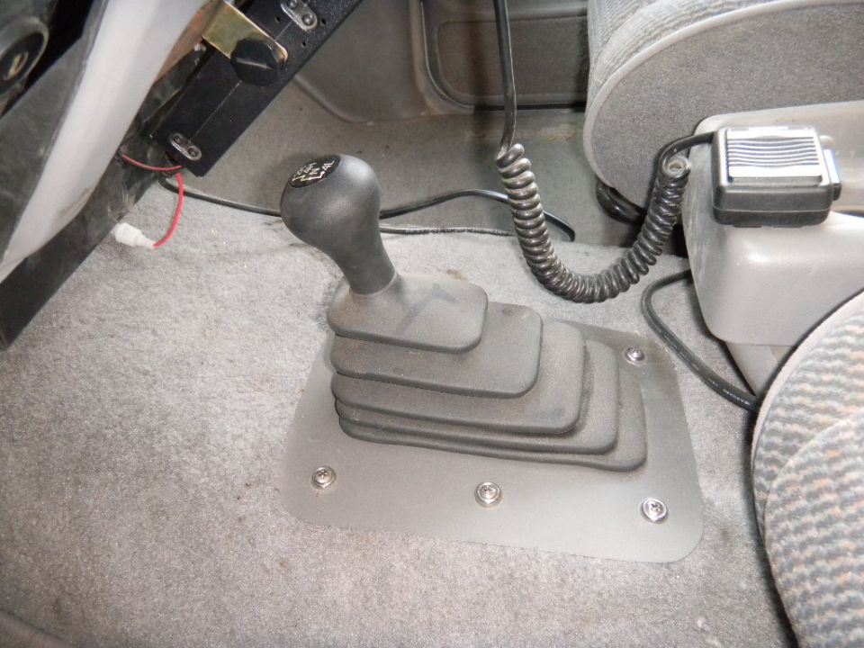 Manual transmission shifter and part of a car interior. A CB radio is mounted on the center console
