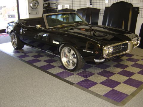 1996 Ford Bronco - A black convertible with a 'Firebird' emblem is displayed indoors on a checkered floor.