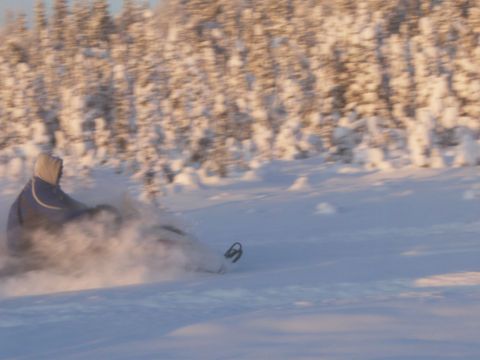 2000 Ford E350 - A snowmobile speeds through a snowy landscape with a rider in a hooded jacket.