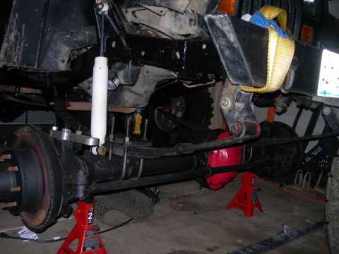 1991 Jeep Wrangler - Close-up of a Jeep's suspension system undergoing modification, showing axle and shock absorber.