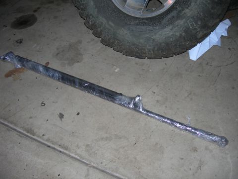 1991 Jeep Wrangler - A metal component, likely a suspension part, is wrapped in plastic and lies on a concrete surface.