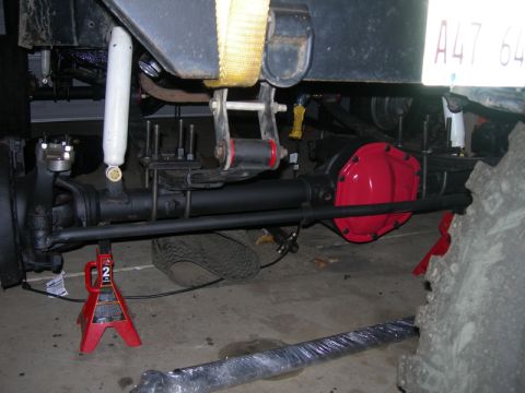 1991 Jeep Wrangler - Underside view of a Jeep's rear axle and suspension components, with a red differential cover visible.