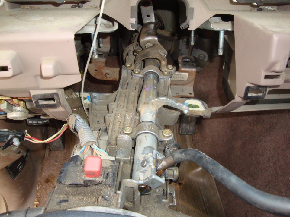 Exposed steering column and wiring under a truck dashboard with dash removed