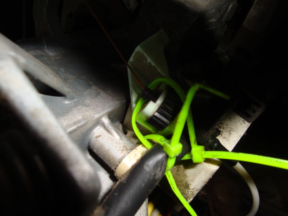 Neon-green cable ties routed around wiring and hose in a dirty engine bay close-up