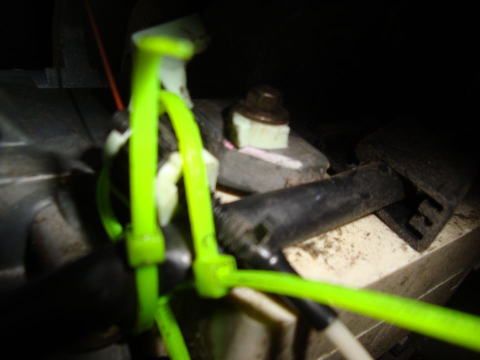 Neon green wiring routed through clips inside a dirty engine bay, close-up