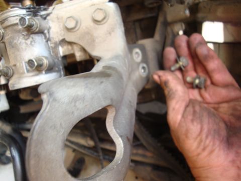1990 Ford Taurus - A mechanic holds bolts near a metal engine component, showing the grime and wear of automotive work.